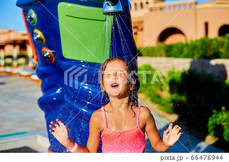 Funny little girl in swimsuit cooling in shower outside Funny little girl in swimsuit cooling in shower outside 66478944