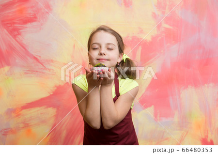Baby girl with closed eyes enjoy eating cupcake 66480353