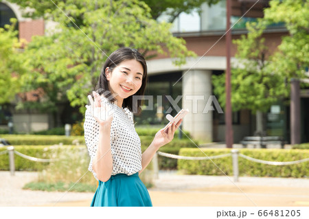 スマホを持って手を振る女性の写真素材