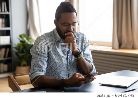 African guy holding smartphone feels concerned thinking over received message African guy holding smartphone feels concerned thinking over received message 66481748