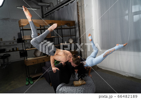 Couple spending time together reading book and making acrobatic balance at home. concept of self-development and creativity. Couple spending time together reading book and making acrobatic balance at home. concept of self-development and creativity. 66482189