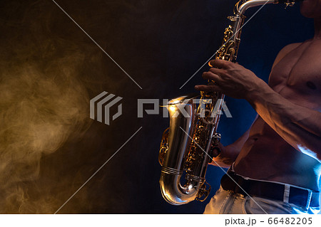 Muscular man naked torso playing on saxophone with smoked colorful background Muscular man naked torso playing on saxophone with smoked colorful background 66482205