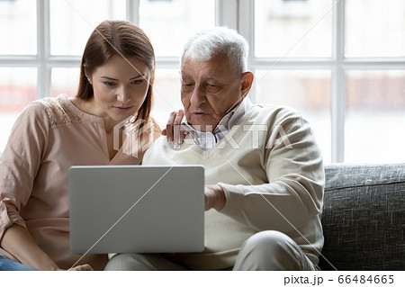 Young woman and older man using laptop together at home 66484665