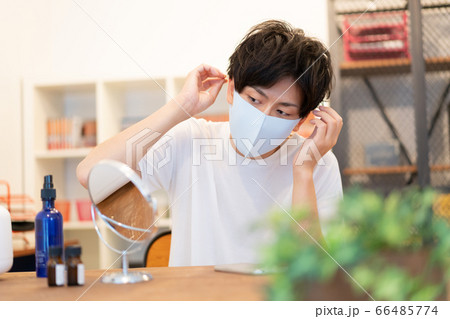 お洒落に気を使って水色のマスクをつけてお出かけの準備をする20代の男子 66485774
