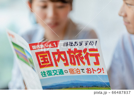 旅行のパンフレットを見ながら計画を立てる男女 66487837