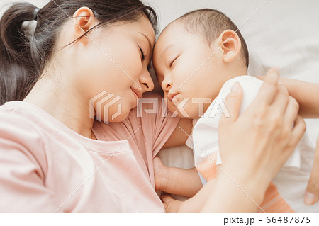 Mother and son sleeping on bed 66487875