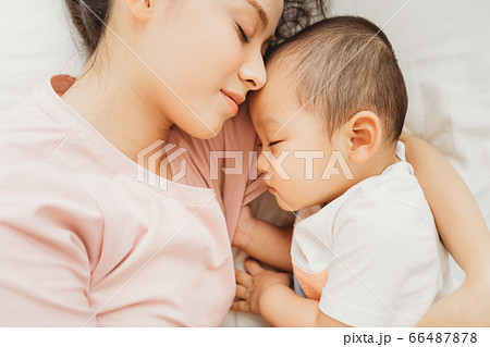 Mother and son sleeping on bed 66487878