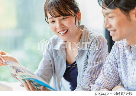 旅行のパンフレットを見ながら計画を立てる男女 66487949