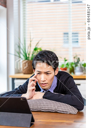 リラックスして自宅でタブレットを見る男性 66488147