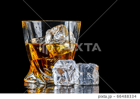 Glass of whiskey with cube ice on black background Glass of whiskey with cube ice on black background 66488334
