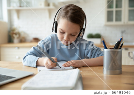 Girl in headphones learning at home doing homework using laptop 66491046