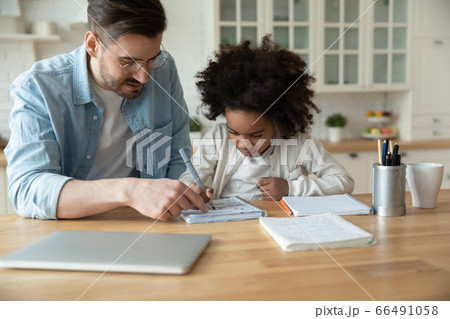 Caucasian stepfather helps with homework little mixed-race daughter 66491058