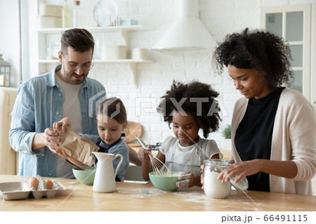 Multiracial family with kids cooking pastries gathered together in kitchen Multiracial family with kids cooking pastries gathered together in kitchen 66491115