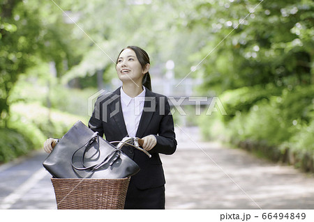 自転車通勤をするスーツ姿の若い女性の写真素材