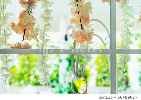 Beautiful artificial flowers hung on glass windows to decorate for a garden party. View from the window on the glass. Beautiful artificial flowers hung on glass windows to decorate for a garden party. View from the window on the glass. 66499027