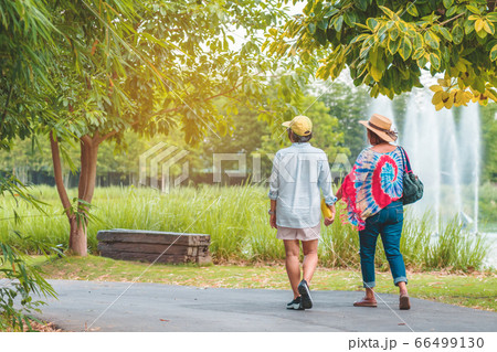Back view of happiness female friends walking together beside the fountain in the public park. Back view of happiness female friends walking together beside the fountain in the public park. 66499130