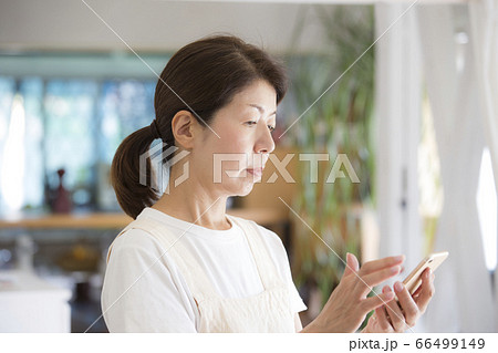 スマホを見る日本人女性、ミドル、主婦、母親 スマホを見る日本人女性、ミドル、主婦、母親 66499149