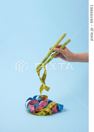 Woman's hand is taking measure tapes by asparagus spears as sticks. 66499861