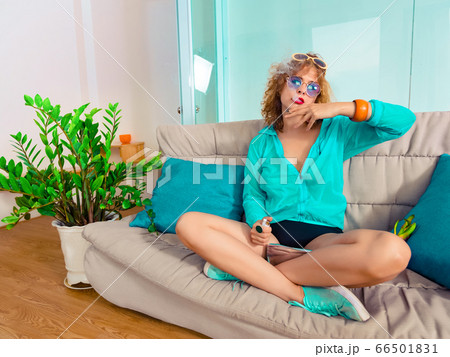 Woman sitting on a sofa smoking sigarette. Self 66501831
