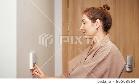 happy woman presses keys of climate control panel in hotel 66503964