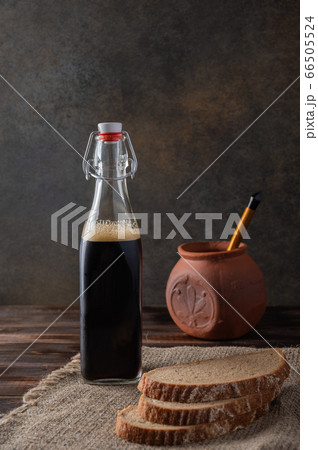 Homemade tradishional russian kvass with glass cup and bread. Behind a clay pot with a wooden spoon Homemade tradishional russian kvass with glass cup and bread. Behind a clay pot with a wooden spoon 66505524