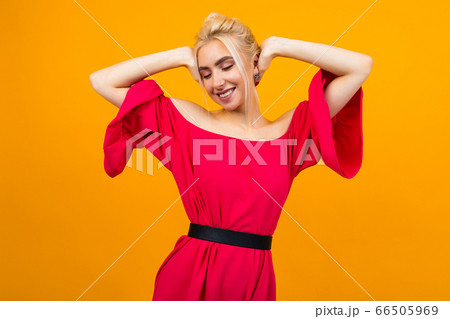 sexy smiling blonde girl in a red dress posing for advertising on a yellow studio background 66505969