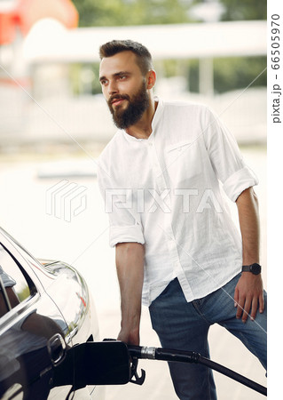 Handsome man pours gasoline into tank of car Handsome man pours gasoline into tank of car 66505970