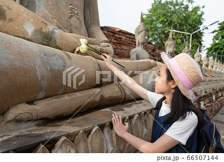 Asian girl tourist holding a lotus with respecting or pray at Wat Yai Chaimngkol, Ayutthaya,Thailand, summer vacation,travel concept. Asian girl tourist holding a lotus with respecting or pray at Wat Yai Chaimngkol, Ayutthaya,Thailand, summer vacation,travel concept. 66507144
