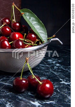 Several red sweet cherries and big green leaf on 66508100