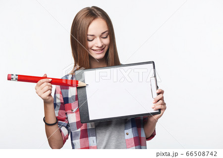 Teen girl holding big pencil and blank paper sheet on tablet Teen girl holding big pencil and blank paper sheet on tablet 66508742