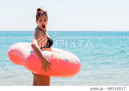 Shocked young woman inside donut rubber ring is Shocked young woman inside donut rubber ring is 66510017