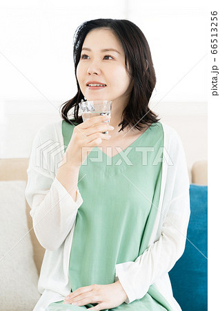 リビングでコップの水を飲むミドル女性 リビングでコップの水を飲むミドル女性 66513256