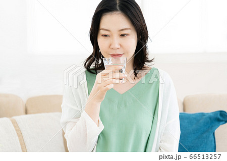 リビングでコップの水を飲むミドル女性 66513257