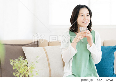 リビングでコップの水を飲むミドル女性 66513258