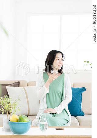 リビングでコップの水を飲むミドル女性 66513263