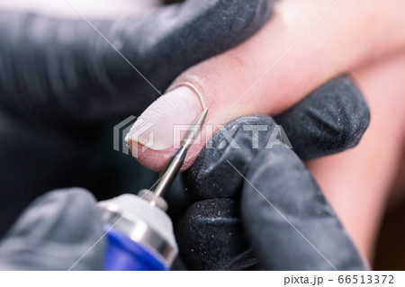 Process manicure close-up. Preparation for hardware manicure. Beautician in rubber gloves cuts the cuticle and processes nails. Process manicure close-up. Preparation for hardware manicure. Beautician in rubber gloves cuts the cuticle and processes nails. 66513372
