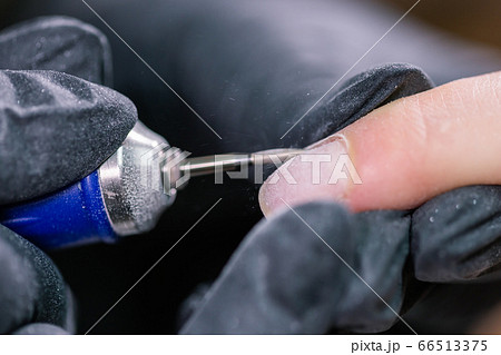 Manicurist use electric nail file drill in beauty salon. Perfect nails manicure process close up with burst flying debris. 66513375