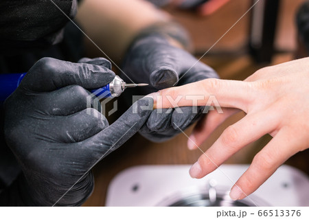 Woman use electric nail file drill in beauty salon. Nails manicure process in detail. Gel polish close-up concept. 66513376