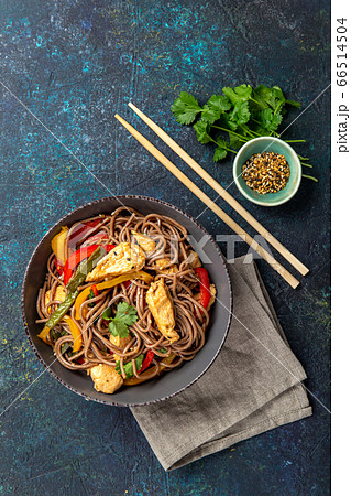 Japanese dish buckwheat soba noodles with chicken and vegetables carrot, bell pepper and green beans in grey bowl, top view, copy space 66514504