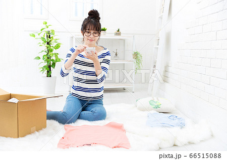 使わなくなった服をネットで売る準備をする女性 66515088