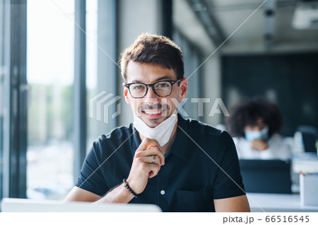 Portrait of young man with face mask back at work in office after lockdown. 66516545
