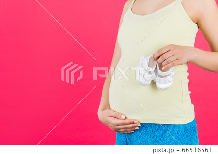 Close up of pregnant woman holding a pair of shoes Close up of pregnant woman holding a pair of shoes 66516561
