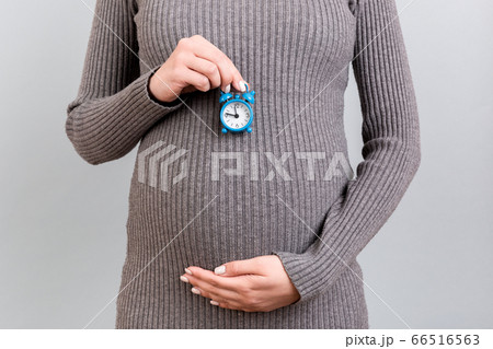 Close up of pregnant woman in gray dress holding Close up of pregnant woman in gray dress holding 66516563