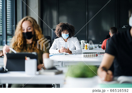 Young people with face masks back at work or school in office after lockdown. 66516592