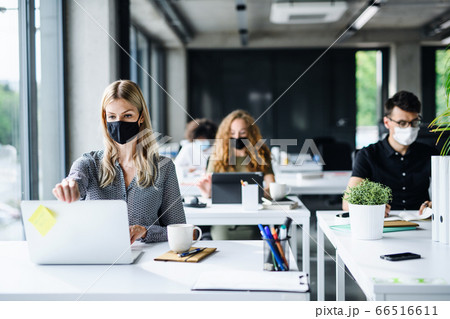 Young people with face masks back at work or school in office after lockdown. Young people with face masks back at work or school in office after lockdown. 66516611