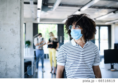 Portrait of young man with face mask back at work in office after lockdown. 66516619
