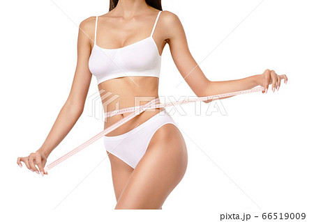Slim tanned woman's body over gray background - waist measurement 66519009