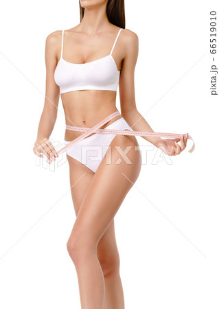 Slim tanned woman's body over gray background - waist measurement 66519010
