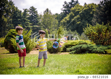 Boy blowing soap bubbles while an excited kid 66521016