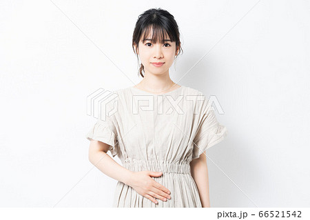 お腹に手を当てる若い女性 66521542